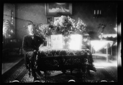 Man sittande vid bord med blommor.
Nyckelord: Blommor Tavla