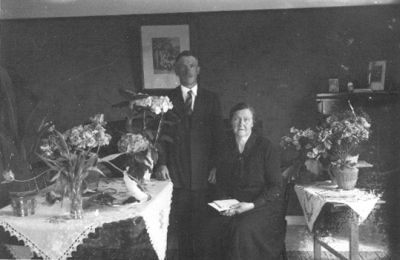 Man stående och kvinna sittande i rum.
Nyckelord: Blommor Tavla