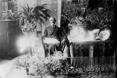 Man sittande vid presentbord i rum.
Nyckelord: Blommor Pelarbord