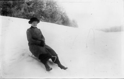 Kvinna sittande på kälke.
Nyckelord: Kjälke Backe Vinter