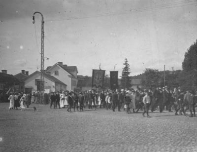 Folksamling på torg
Nyckelord: Kullersten Banderoll Lyktstolpe Hund