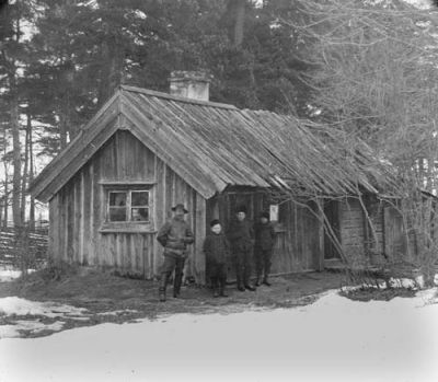 1 man och 3 pojkar framför byggnad
