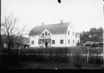 Byggnad bakom häck.
Nyckelord: Häck