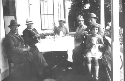 3 män, 2 kvinnor och 1 flicka sittande på veranda vid kaffebord.
Nyckelord: Veranda Kaffe