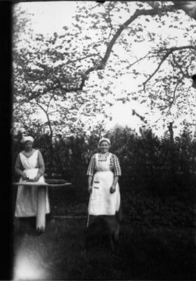 2 kvinnor stående vid bord i trädgård.
Nyckelord: Bord Natur