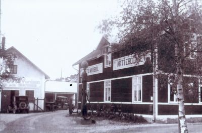 2 bilar på gårdsplan framför byggnad
Nyckelord: Bil