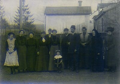 Män kvinnor och barn stående på en grusplan
Nyckelord: Familj, Dräkt