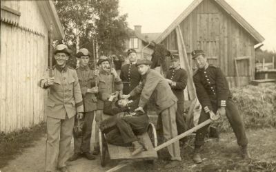 8 militärer framför byggnader
Keywords: Skottkärra Uniform Väska