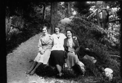 3 kvinnor sittande på sten i skogsbacke.
Nyckelord: Sten Stig Skog