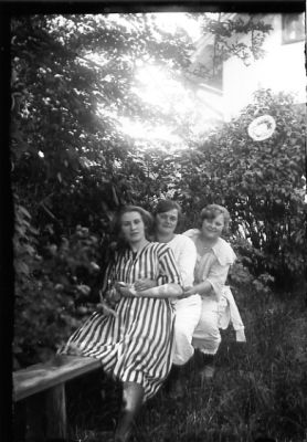 3 kvinnor sittande på bänk i trädgård.
Nyckelord: Bänk Växtlighet