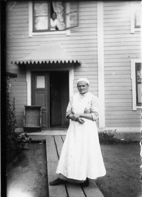 Kvinna stående på trägolv framför byggnad.
Nyckelord: Trägolv Bostad