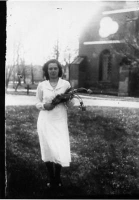 Kvinna stående framför kyrka med blommor i famnen.
Nyckelord: Blommor