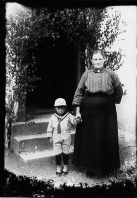 Kvinna och pojke stående framför byggnad.
