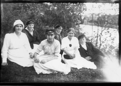 2 män och 4 kvinnor sittande i skogsbacke.
