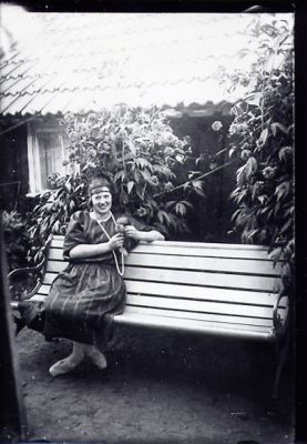 Kvinna sittande på parkbänk framför byggnad.
Nyckelord: Parkbänk