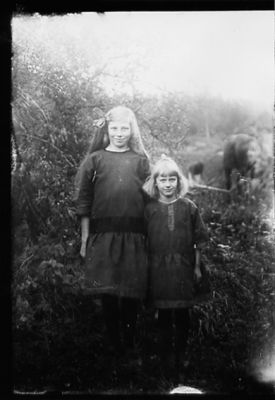 2 flickor stående i naturen.
