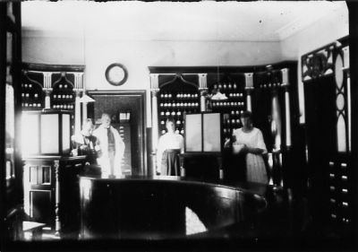 2 män och 2 kvinnor stående bakom disken i apotek.
Nyckelord: Klocka Burkar