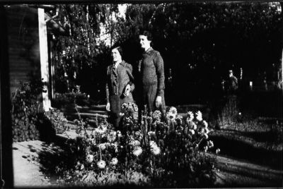 2 kvinnor stående bland blommor i trädgård.
Nyckelord: Blommor