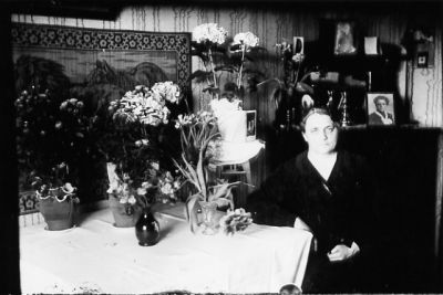 Kvinna sittande i rum med blommor.
Nyckelord: Högtid Blommor