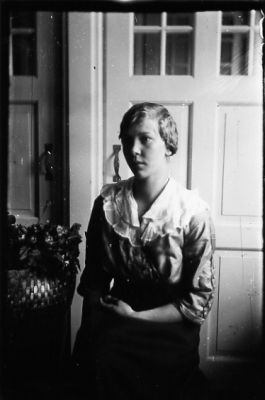 Kvinna stående framför dörr.
Nyckelord: Dörr