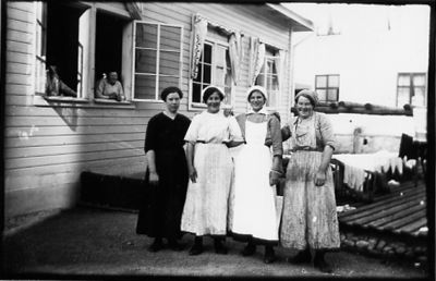 4 kvinnor stående på bakgård.
Nyckelord: Bakgård