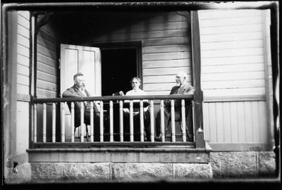 2 män och 1 kvinna sittande på veranda.
Nyckelord: Veranda