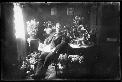 Man sittande i rum med blommor.
Nyckelord: Blommor