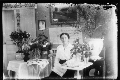 Kvinna sittande i rum med blommor.
Nyckelord: Blommor Tavla