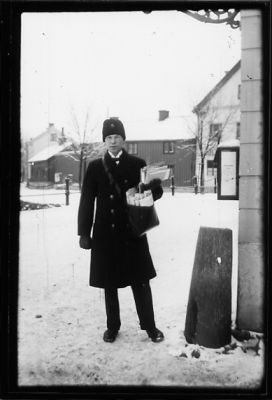 Brevbärare stående med postväska vid brevlåda.
Nyckelord: Uniform Post Vinter