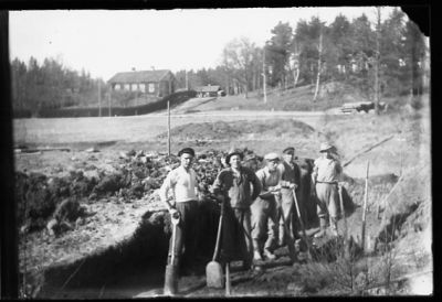 5 män stående med spadar i handen vid vägarbete.
Nyckelord: Spade