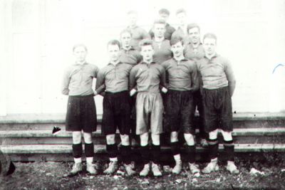 11 fotbollsklädda män stående framför byggnad.
Nyckelord: Fotboll