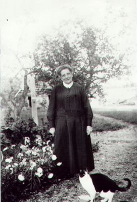 Kvinna stående vid rabatt.
Nyckelord: Katt Blommor