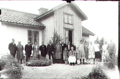 Ett antal personer samlade framför byggnad.
Nyckelord: Trädgård Bostad