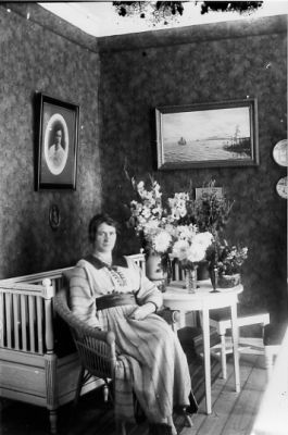 Kvinna sittande vid bord med blommor.
Nyckelord: Högtid Tapet Tavla Blommor