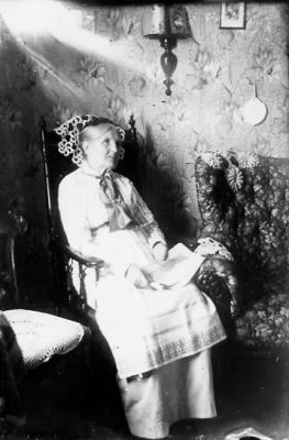 Kvinna sittande i rum.
Nyckelord: Tapet Lampa
