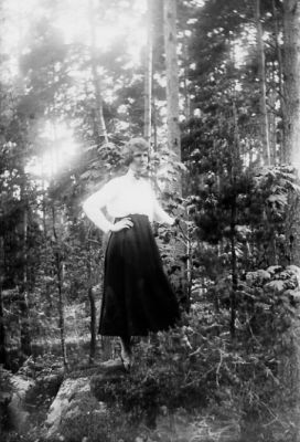 Kvinna stående i skogsbacke.
Nyckelord: Skog