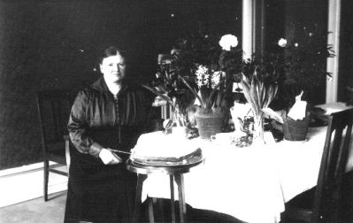 Kvinna sittande vid bord med blommor.
Nyckelord: Blommor