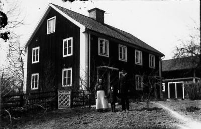 Man, kvinna och pojke stående framför byggnad.
Nyckelord: Trädgård