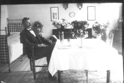 Man sittande vid bord med blommor.
Nyckelord: Blommor Säng