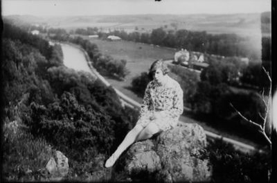 Kvinna sittande på berg med vattendrag i bakgrunden.
Nyckelord: Utsikt
