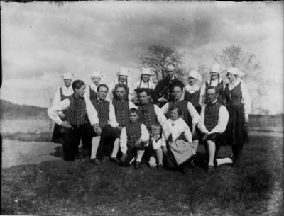 Folkdanslag samlade på gräsmatta.
Nyckelord: Folkdanslag