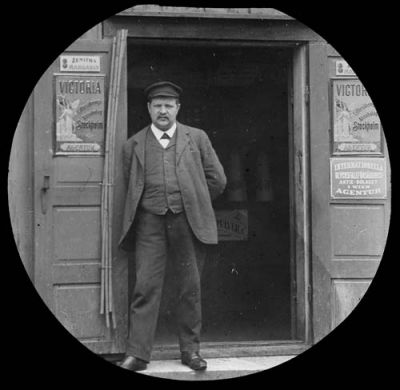 Man i dörröppning till handelsbod
Nyckelord: Reklamskylt