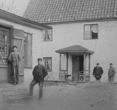 4 män på gårdsplan framför byggnad
