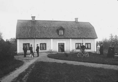 4 män 4 kvinnor 1 pojke och 1 hund framför byggnad
Nyckelord: Hund Cykel