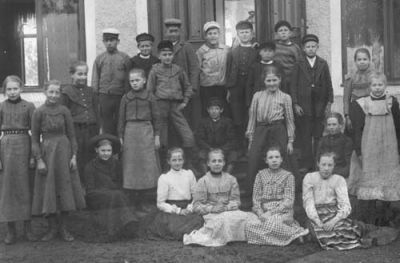 Kvinna pojkar och flickor framför byggnad
