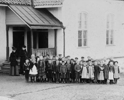 2 kvinnor och många barn framför hus
