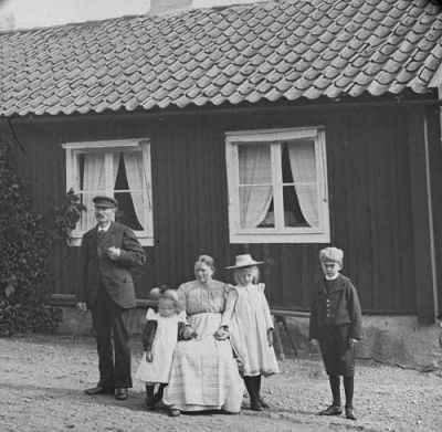 Man kvinna pojke och 2 flickor framför byggnad
