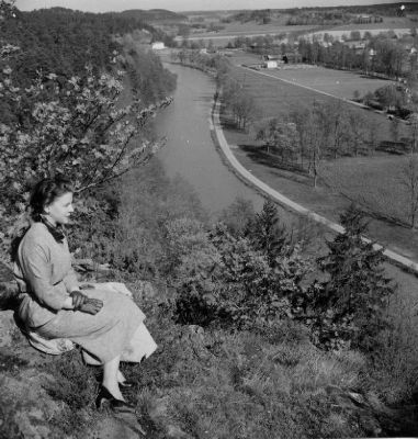 Kvinna sittande på berg med utsikt över vattendrag
