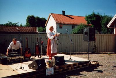 Kvinna i folkdräkt som talar från utescen
Nyckelord: Musikinstrument Dräkt