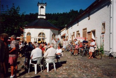 En grupp människor samlade på kullerstensbelagd innergård
Nyckelord:  Café Servering